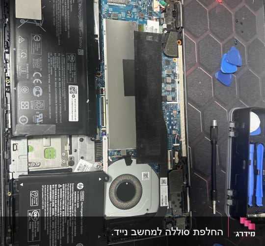 מחשב נייד פתוח עם סוללה, מאוורר וכלי עבודה